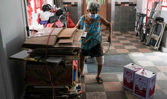 Mdm Ooi at the corridor outside her home with the cardboard she has collected.
